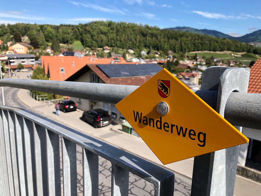 A yellow Swiss Wanderweg sign with the Bern coat of arms